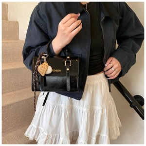 Close-up of black retro handbag with FASHION lettering and cute cookie pendant