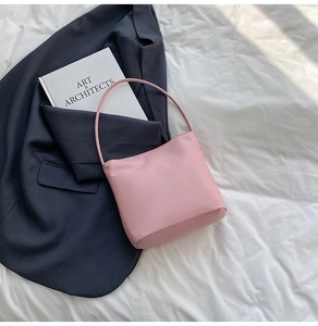 Chic pink hobo shoulder bag with round handle styled with art books for a modern look
