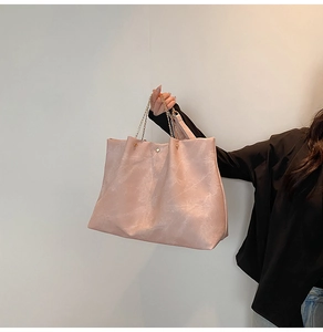 Détail d'un sac cabas rose montrant le cuir texturé et la bandoulière en chaîne dorée
