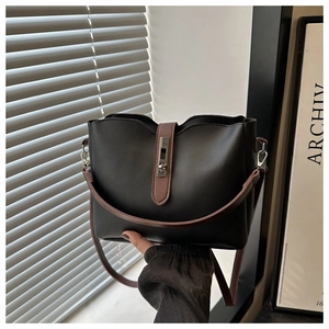 Détail du sac seau en cuir noir avec bandoulière marron contrastée et boucle argent