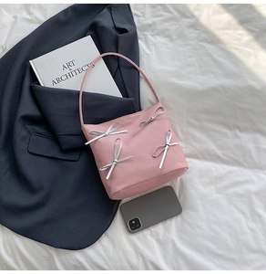 Detailed shot of pink satin shoulder bag with silver bows on a minimalist white backdrop
