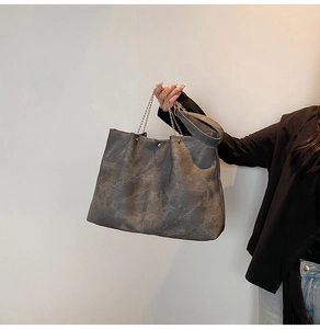 Détail du cabas en cuir gris à texture marbrée avec des poignées en chaîne métallique