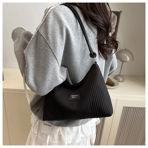 Detail view of the pleated texture and brand tag on a black large shoulder bag
