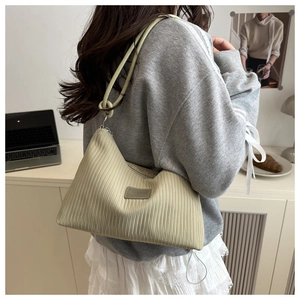 Detail of the pleated texture and leather brand tag on a large tote shoulder bag