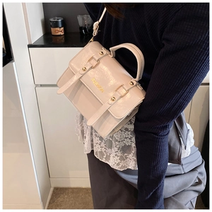 Chic cream white crossbody bag with gold hardware shown on a model in a lifestyle setting