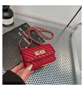 Detailed close-up of a red quilted mini bag with gold twist lock and chain strap