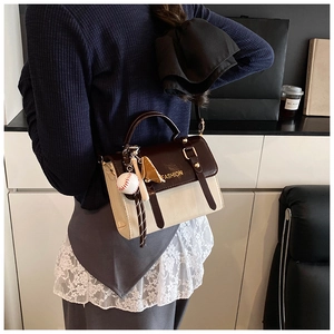 Detail of vintage crossbody bag showing contrast panels and a baseball charm on the side