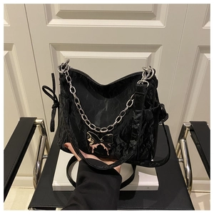 Detail of black pleated fabric bag with silver liquid metal butterfly pendant and chain