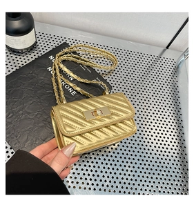 Detailed view of golden quilted mini crossbody bag with metal twist lock and chain strap