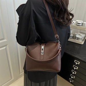 Sac seau minimaliste marron café avec fermoir argenté porté à l'épaule par un mannequin