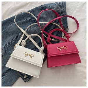 Detail of mini leather crossbody bags in white and rose red with gold bow accents