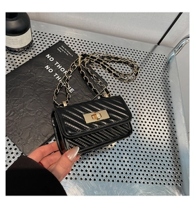 Detail of black chevron quilted crossbody bag with golden hardware and chain strap