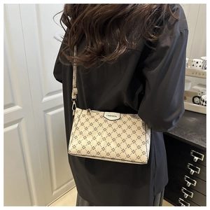 Detail of beige rectangular PU crossbody bag featuring black star pattern and leather label