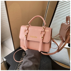 Detail of pink PU leather handbag with gold metal rivets and adjustable strap