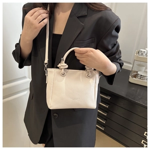 Model showing off-white pebbled leather bucket bag with knotted handles and logo detail