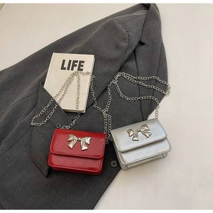 Close-up of mini crossbody bags with silver metal bow detail and sleek chain straps