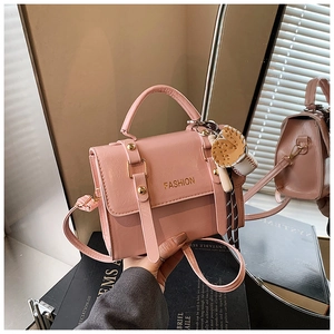 Detail of pink glossy leather handbag with fashion lettering and baseball charm