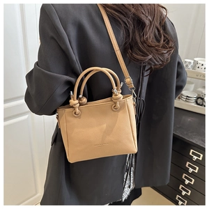 Detail of camel leather bucket bag with knot handles and textured lychee grain finish