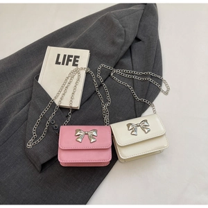 Close-up of pink and beige chain bags with metallic bow details on a stylish blazer