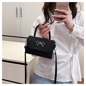 Detail of black sequined crossbody bag with silver bow clasp and glittery finish