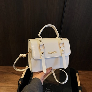 Detail of white rectangular handbag with gold Fashion text and metallic rivet hardware