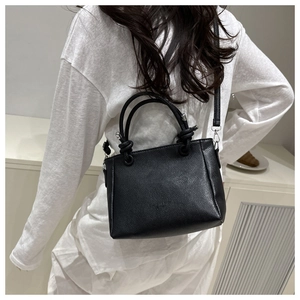 Detail of black pebbled leather handbag with knotted circular handle and silver hardware