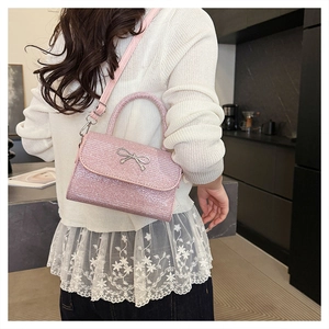 Pink sequin crossbody bag with silver bow hardware worn by model in a casual setting