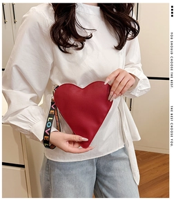 Detail der roten Herz-Clutch aus Litschi-Leder mit bunten LOVE-Aufdruck auf der Handschlaufe