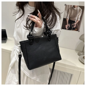 Detail of black pebbled leather tote with knot handle and adjustable shoulder strap