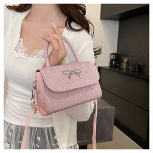 Macro shot of glittery pink handbag featuring a silver metal bow buckle and slim strap