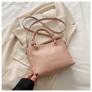 Detail of light pink bucket bag with knotted handle and fashion leather lettering