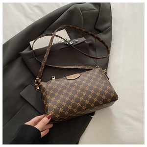 Detailed shot of brown monogram crossbody bag with gold hardware on grey suit jacket
