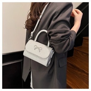 Sparkly silver sequin crossbody bag with bow detail worn by model on suit