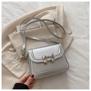 Close-up of a silver bow buckle and leather texture on a stylish crossbody bag