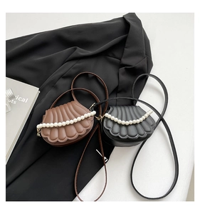 Détail de sacs en forme de coquillage avec texture matelassée et décorations en perles