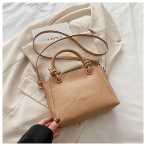 Close-up of caramel pebbled leather bucket bag with knot handle and metal hardware