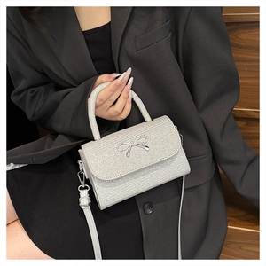 Silver glitter mini handbag with metal bow detail shown on a model in a black suit