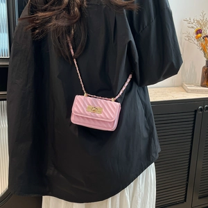 Pink quilted leather mini crossbody bag with gold chain strap shown on model shoulder