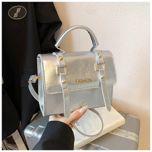 Close-up of silver metallic crossbody bag with textured pleats and golden rivet accents