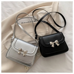 Detail of trendy crossbody bags featuring metallic bow buckles in silver and black colors