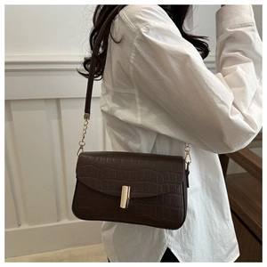 Detail of dark brown crocodile pattern shoulder bag with metal buckle and chain strap