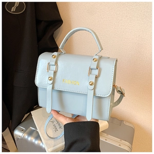 Close-up of light blue leather handbag with gold studs and handle in a lifestyle setting