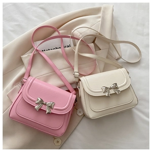 Detail of pink and cream small square crossbody bags with metallic bow clasps