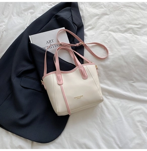 Detail of elegant cream tote bag with pink trim, gold hardware and fashion lettering