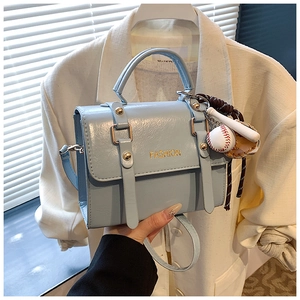 Detail of light blue faux leather square bag with baseball charm and fashion lettering