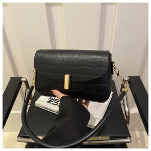 Close-up of black crocodile pattern faux leather bag with elegant gold metal clasp