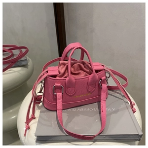 Close-up of pink litchi grain leather handbag with drawstring liner and gold lettering