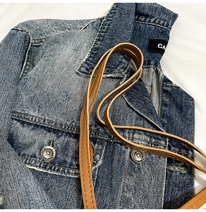 Detailed macro view of vintage blue denim fabric texture and CARGOAZ branded metal buttons