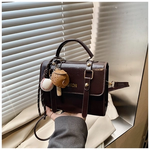 Detail of vintage brown crossbody bag with gold hardware and baseball charm