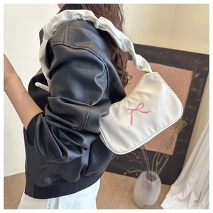 Dettaglio di borsa baguette bianca con ricamo a fiocco rosa e tracolla con effetto arricciato